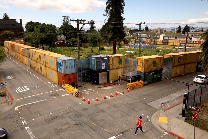 BERKELEY, CA - APRIL 26, 2024 - A pedestrian walks outside People's Park surrounded by shipping containers in Berkeley on April 26, 2024. The California Supreme Court on Thursday ruled that UC Berkeley can proceed with its controversial plan to build high-rise student housing on the site of storied People's Park. (Genaro Molina/Los Angeles Times)