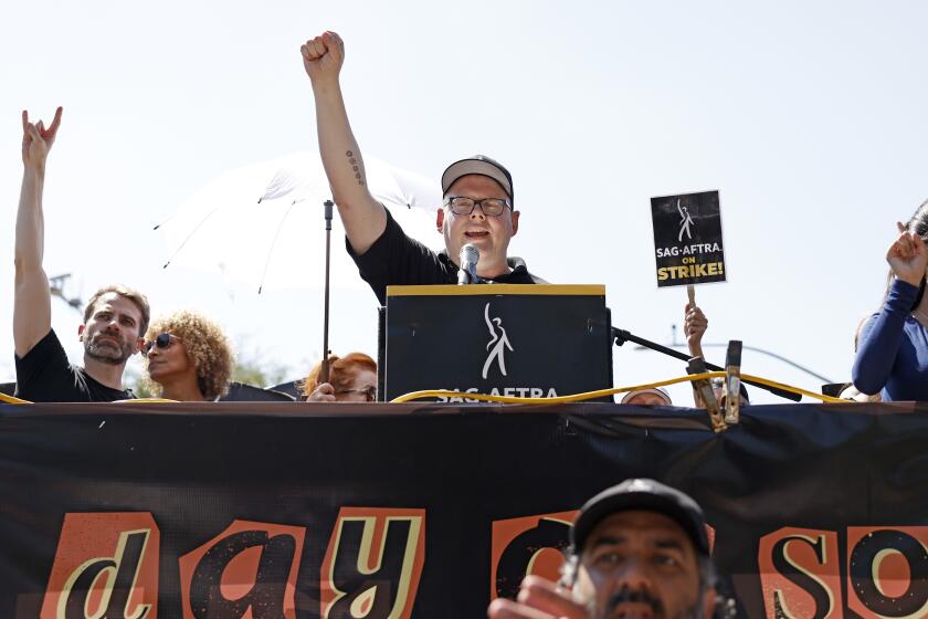 Duncan Crabtree-Ireland raises his fist while speaking at a podium at a demonstration.