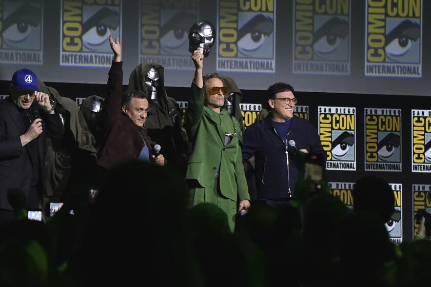 Kevin Feige (left) Joe Russo, Robert Downey Jr., and Anthony Russo standing on stage at Comic-Con. 