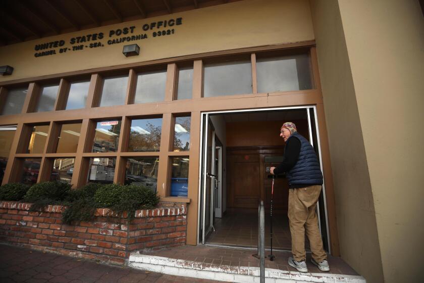 CARMEL-BY-THE-SEA, CA - JANUARY 12, 2024 - - Hans Lehmann, 91, heads into the post office to collect his mail in downtown Carmel-By-The-Sea on January 12, 2024. Because there are no street addresses in the city, Lehmann, who has lived in Carmel since 1939, has to pick up his mail from the post office box. He finds the post office a good place to meet friends, enjoy a conversation and embrace the strong sense of community on his daily trips. Carmel-By-The-Sea has never had street addresses - except the post office - and does not have at-home postal delivery. The town is now debating about getting addresses because it's hard to get packages, and Medicare coverage, when you don't have a physical address. More places don't accept PO Boxes. (Genaro Molina/Los Angeles Times)