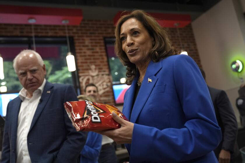 Democratic presidential nominee Vice President Kamala Harris holds a bag of Doritos chips as Democratic vice presidential nominee Minnesota Gov. Tim Walz looks on at Sheetz convenience store during a campaign stop, Sunday, Aug. 18, 2024, in Coralpolis, Pa. (AP Photo/Julia Nikhinson)