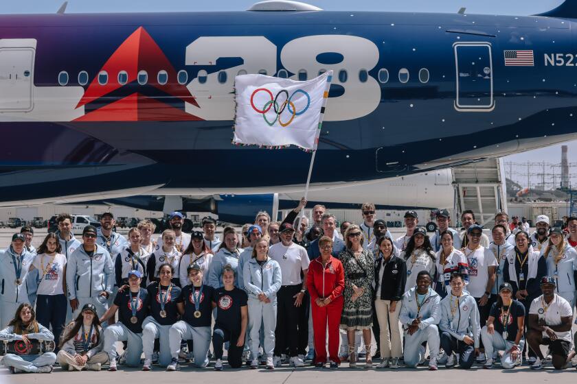 L.A. mayor Karen Bass and Gov. Gavin Newsom pose for a photograph with the official Olympic flag as it returns to LA