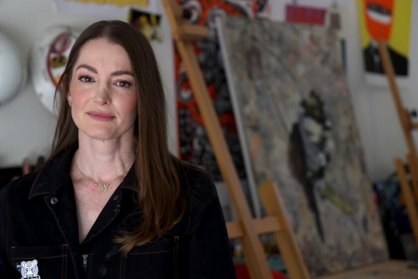 Miriam Hellmann stands in her garage with artworks created by her and other scenic painters.