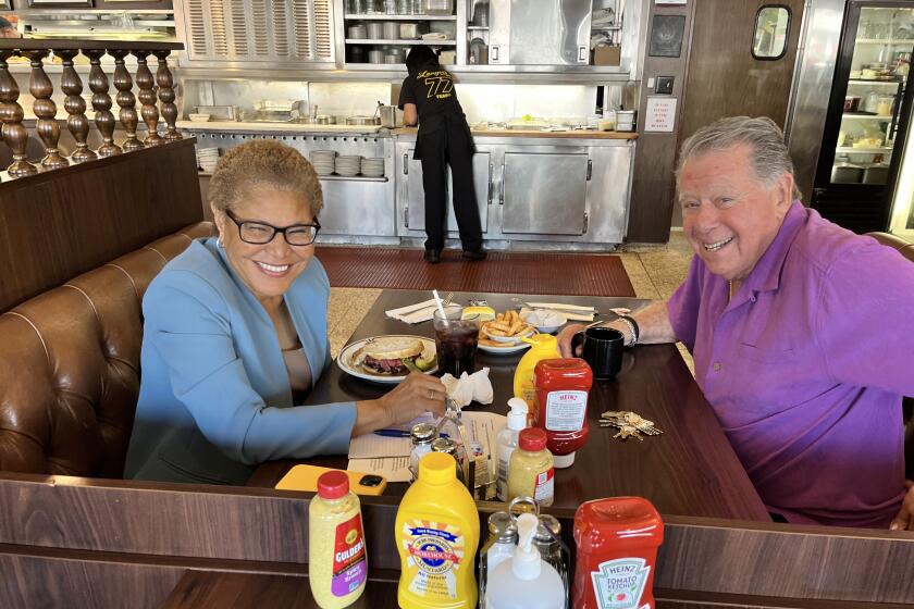 Los Angeles Mayor Karen Bass, left, visits with Norm Langer at the deli that bears his name, Langer's Deli. Last week he said he was thinking about closing the iconic restaurant.