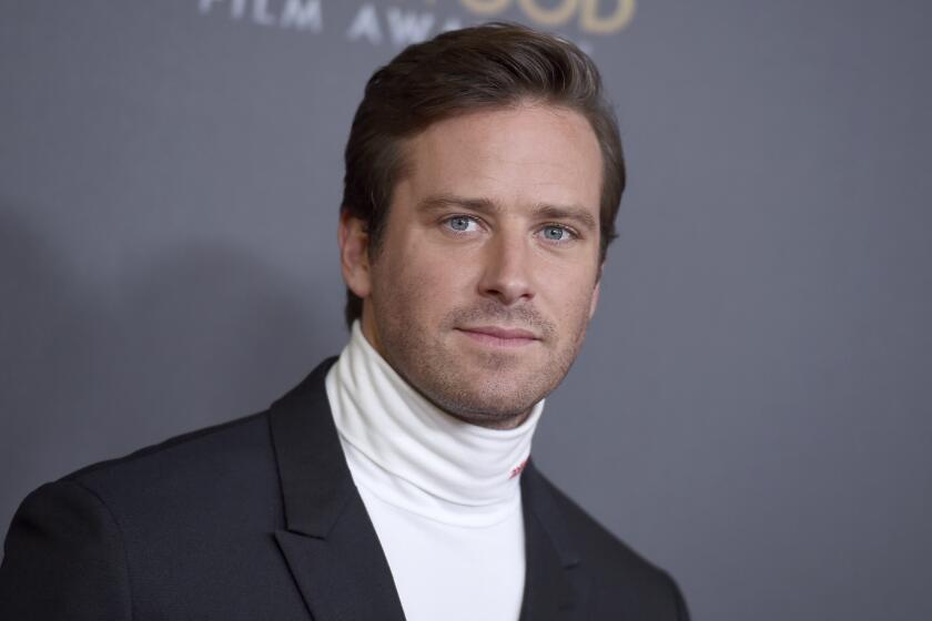 
Armie Hammer poses in a white turtleneck shirt and black blazer