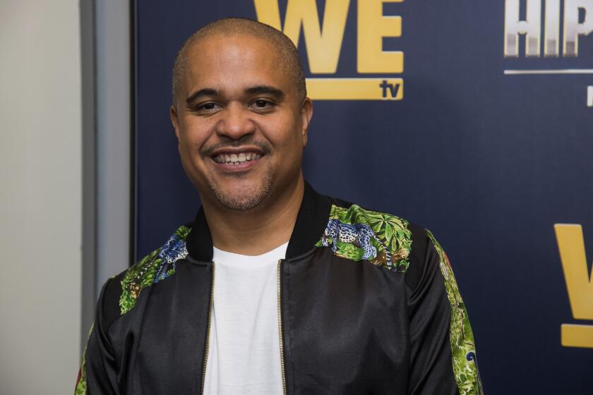 Irv Gotti smiles in a white t-shirt and a black embellished bomber jacket