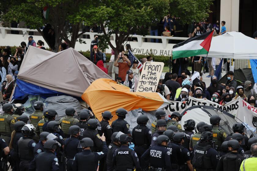 Irvine, CA - May 15: Pro-Palestine demonstrators face off with multiple police agencies forming a containment line, and arrest protesters as they break up the pro-Palestine encampment at UCI in Irvine Wednesday, May 15, 2024. A protest at UC Irvine regarding the war in Palestine has turned violent, prompting calls for police and a warning to students and educators on campus. Protesters have surrounded the physical sciences lecture hall, which has been closed off. (Allen J. Schaben / Los Angeles Times)